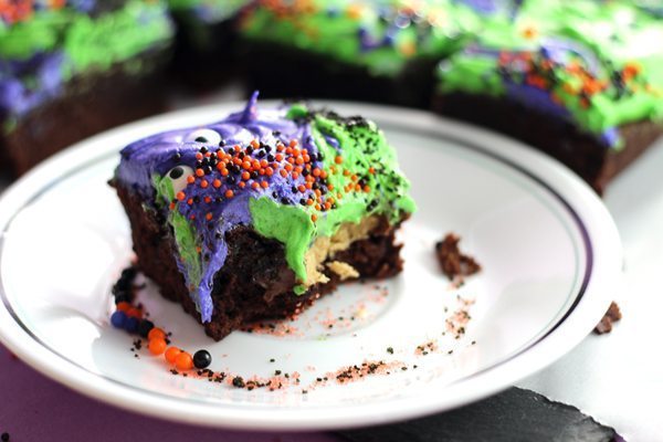 Rich brownies frosted with bright purple and green buttercream with peanut butter cup centers