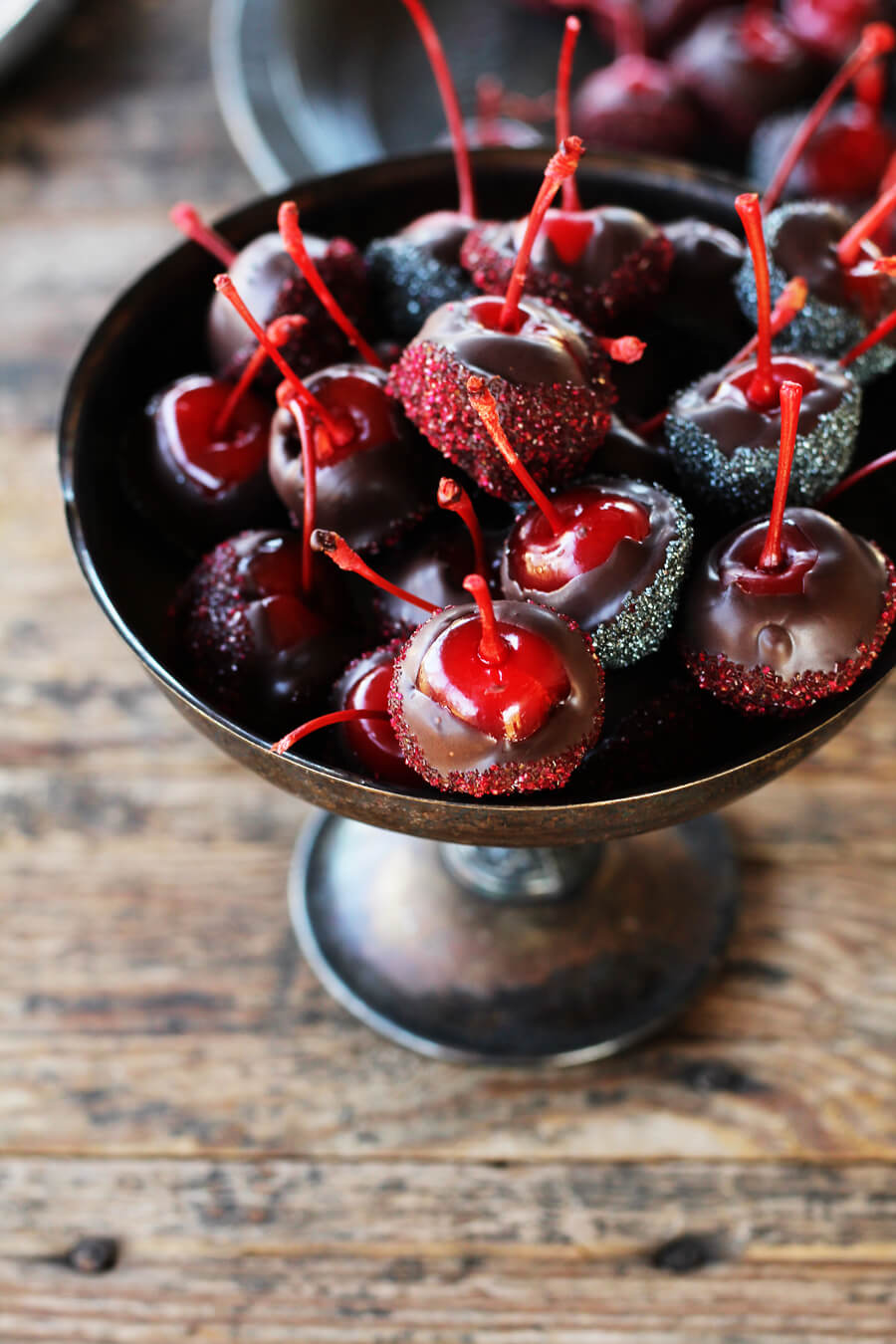 A vintage silver serving dish filled with chocolate covered cherries.
