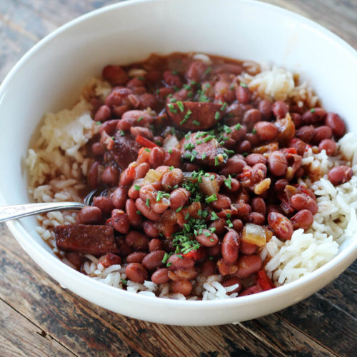 A white bowl with rice, red beans, smoked sausage