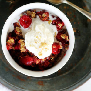 overhead picture of a white bowl with a warm cherry dessert topped with ice cream