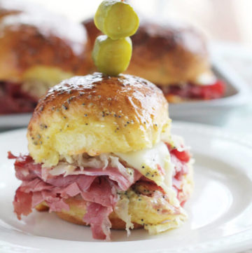 close up picture of a small slider with corned beef, sauerkraut and cheese